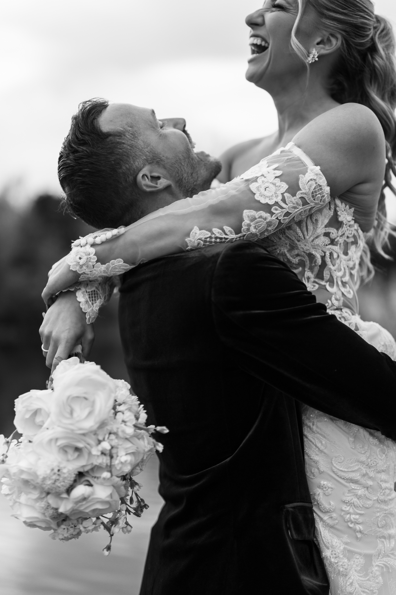 Groom lifting bride as she laughs with pure joy
