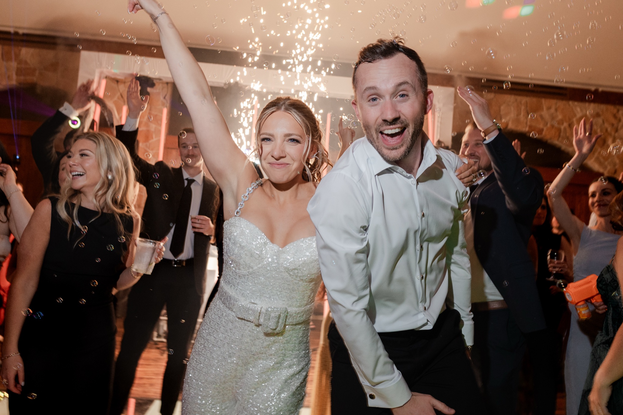 Crowd cheering with bubbles and sparklers at a wedding reception