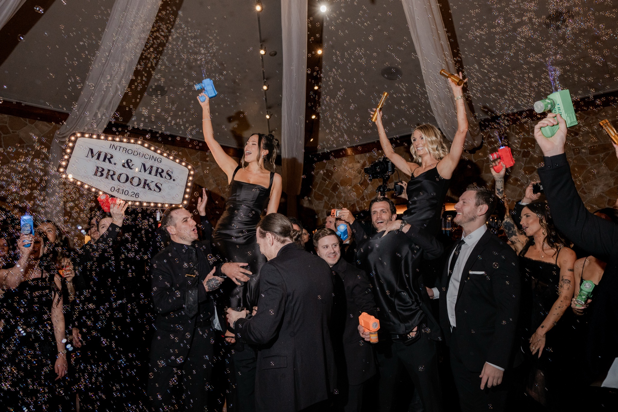 Bridal party entrance — bubbles, Mr & Mrs Brooks sign, and pure joy