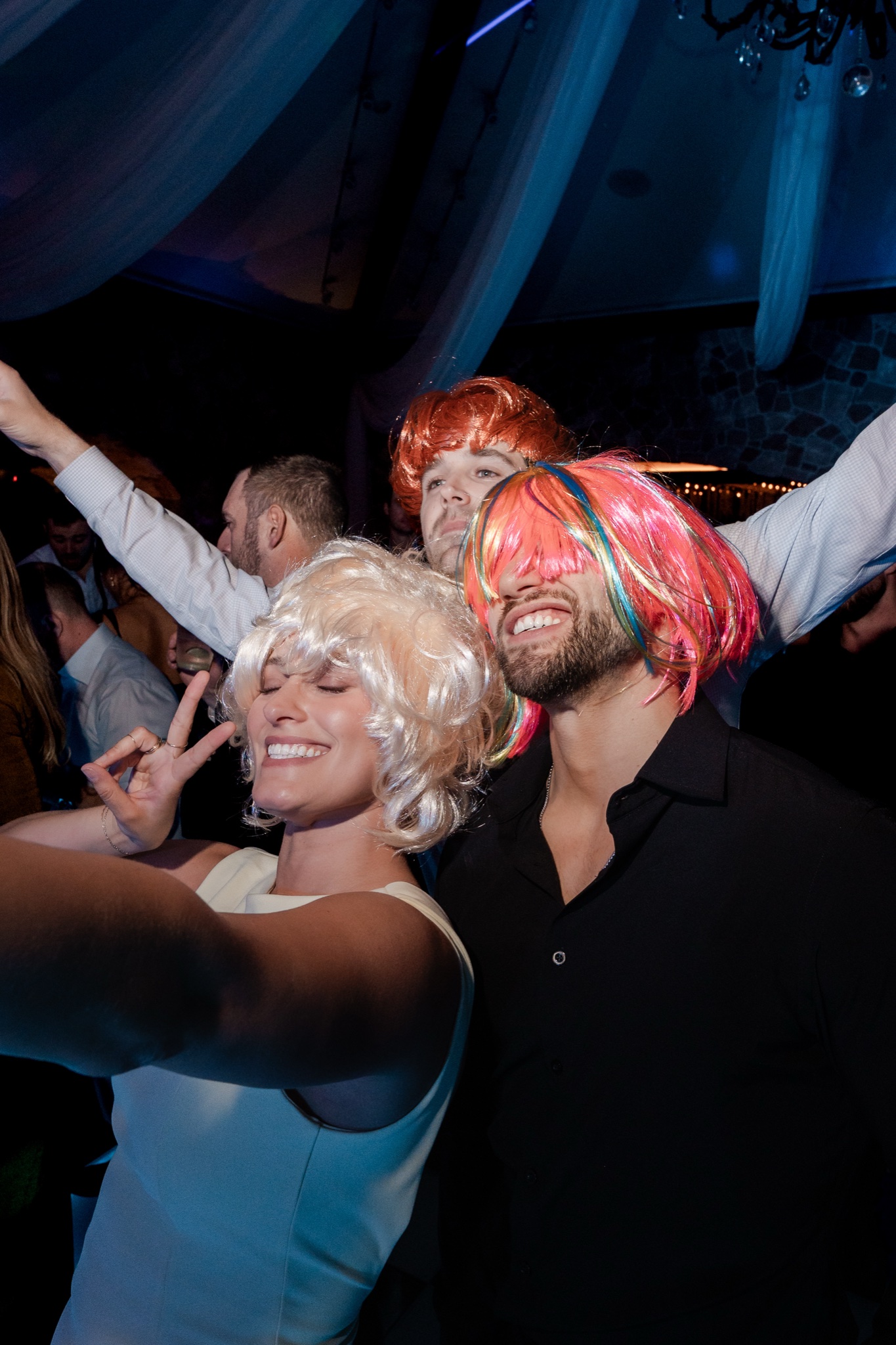 Guests taking selfies wearing wigs at the wedding