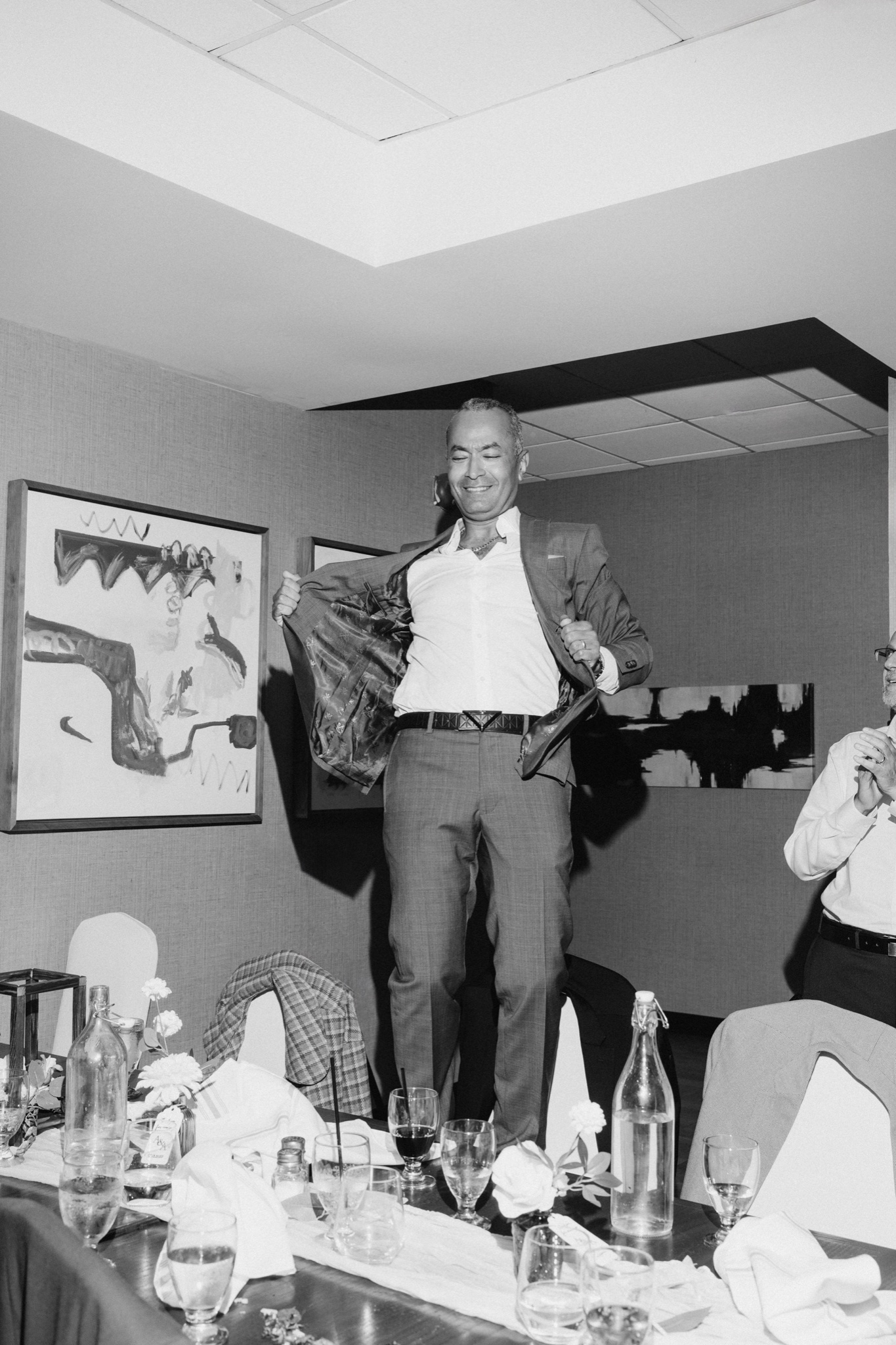 Dad dancing on top of a table at the reception — black and white